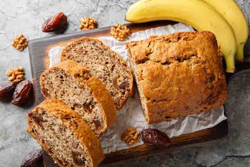Gluten free and lactose free Date banana walnuts bread loaf close up on wooden board on table. Horizontal top view from above